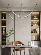 Clérachic pendant above a marble desk with a tan chair, in front of lit shelves holding books, a bust and a plant.