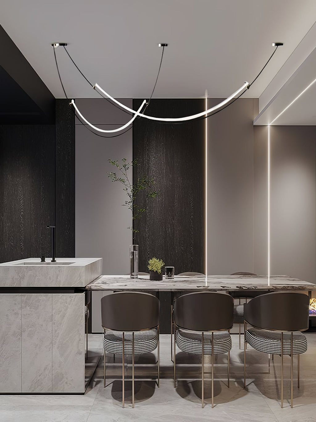 This Clérachic pendant in a dark, modern dining space, above a marble table with brown striped chairs and a stone kitchen block.