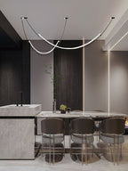 This Clérachic pendant in a dark, modern dining space, above a marble table with brown striped chairs and a stone kitchen block.