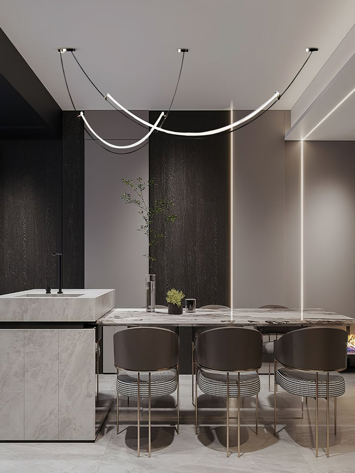 This Clérachic pendant in a dark, modern dining space, above a marble table with brown striped chairs and a stone kitchen block.