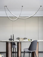 Clérachic pendant over a marble-topped table on bronze cylindrical legs, with a grey chair and black candlesticks below.