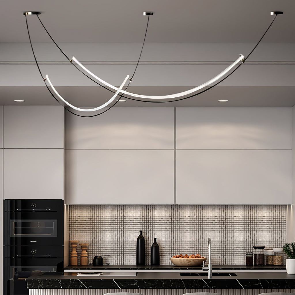Clérachic pendant lit in a white kitchen with a mosaic splashback, black built-in oven and a bowl of fruit on the counter.