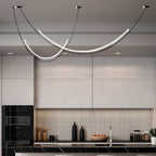 Clérachic pendant lit in a white kitchen with a mosaic splashback, black built-in oven and a bowl of fruit on the counter.