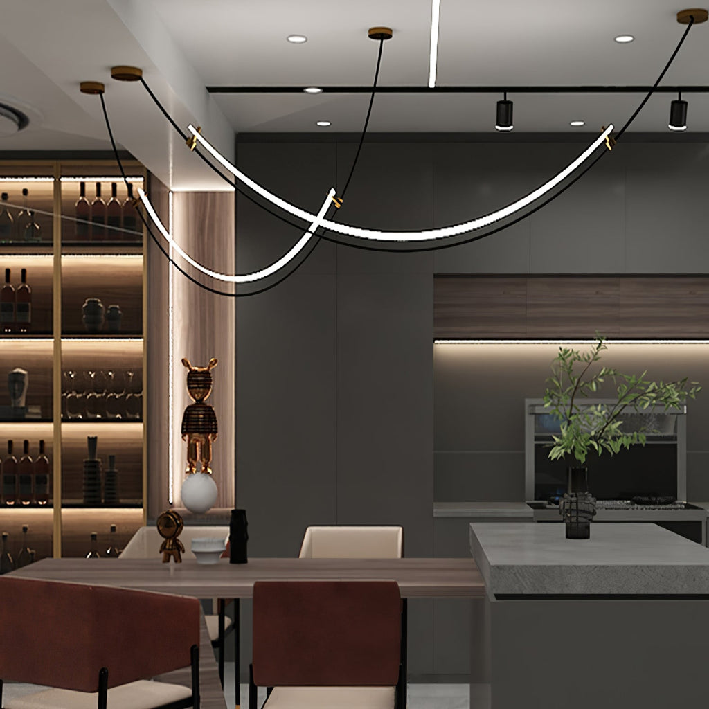Clérachic pendant with gold-tipped canopies in a dark kitchen and dining space, beside a lit wine shelf and a black-and-white figure.