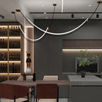 Clérachic pendant with gold-tipped canopies in a dark kitchen and dining space, beside a lit wine shelf and a black-and-white figure.
