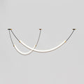 Lit Clérachic pendant on a pale grey backdrop, two staggered LED bars hung from three small canopies on thin black cables.