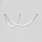 Lit Clérachic pendant on a pale grey backdrop, two staggered LED bars hung from three small canopies on thin black cables.