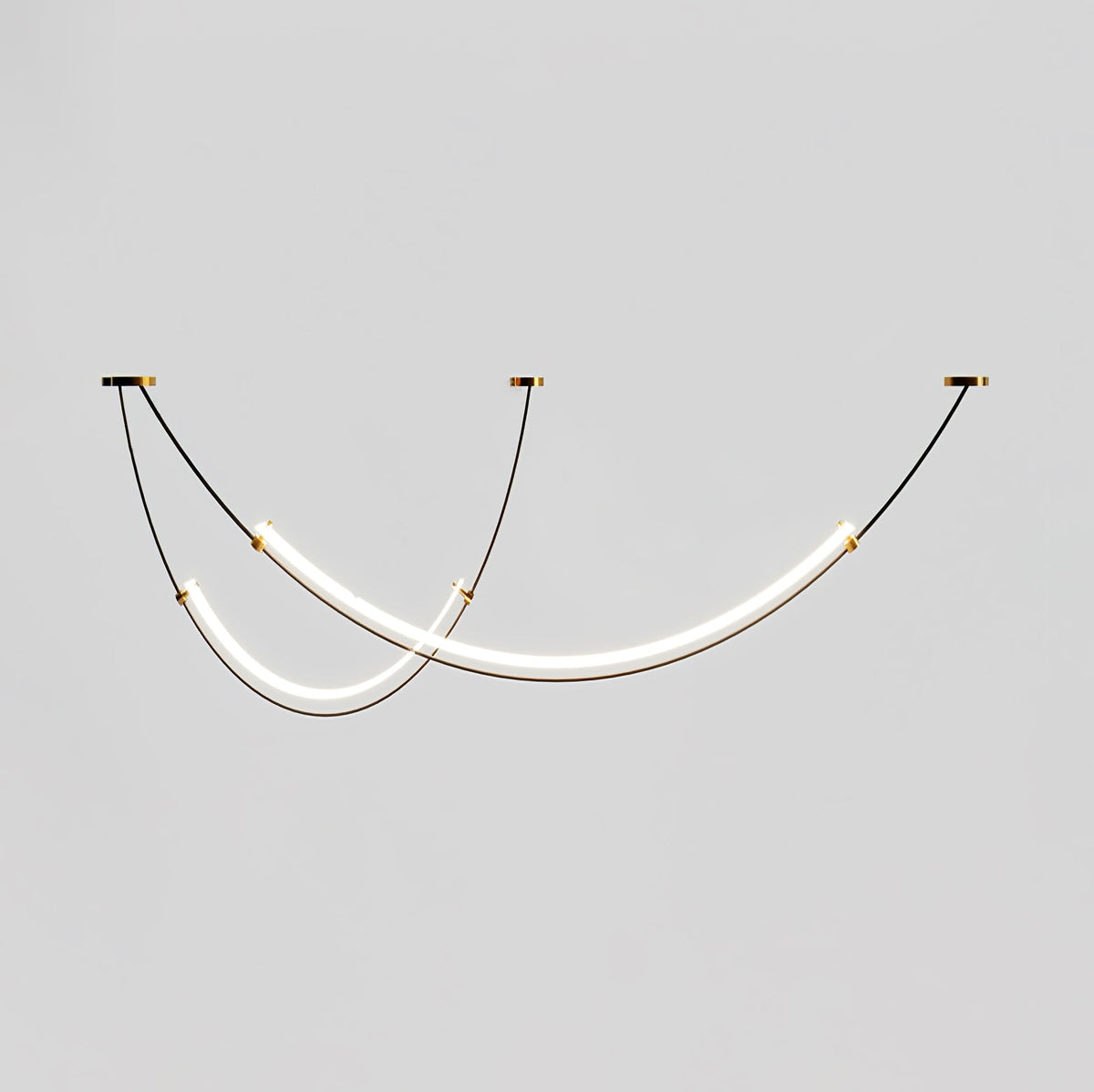 Lit Clérachic pendant on a pale grey backdrop, two staggered LED bars hung from three small canopies on thin black cables.
