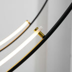 Close view of a gold collar joining the glowing LED bar to the black arm on this Clérachic pendant, with a second bar behind.