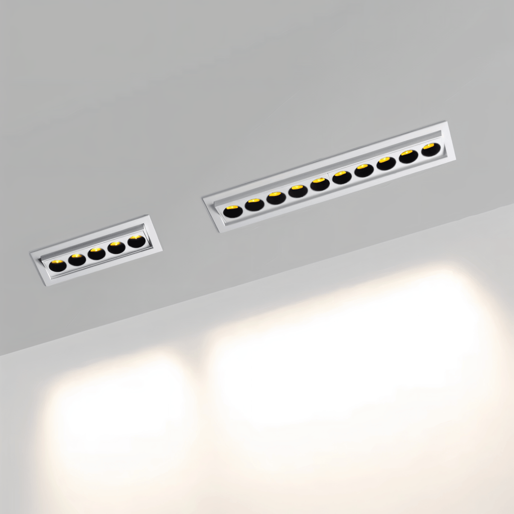 Clérachic white recessed downlights, a five-reflector and a ten-reflector size side by side, lit warm and washing a pale wall below.