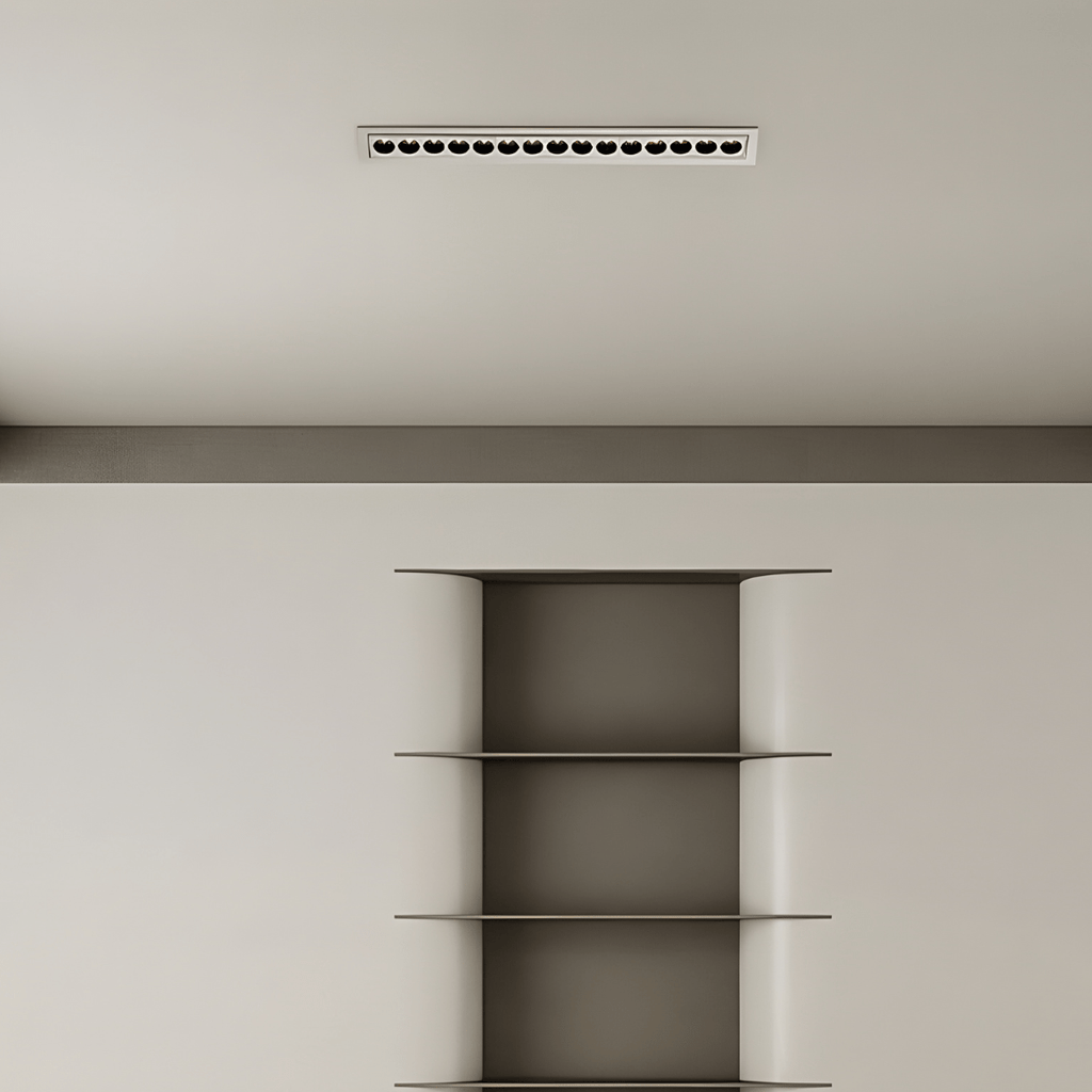 Clérachic long white recessed linear downlight with small black reflectors, centred on a plain ceiling above a metal shelving niche.