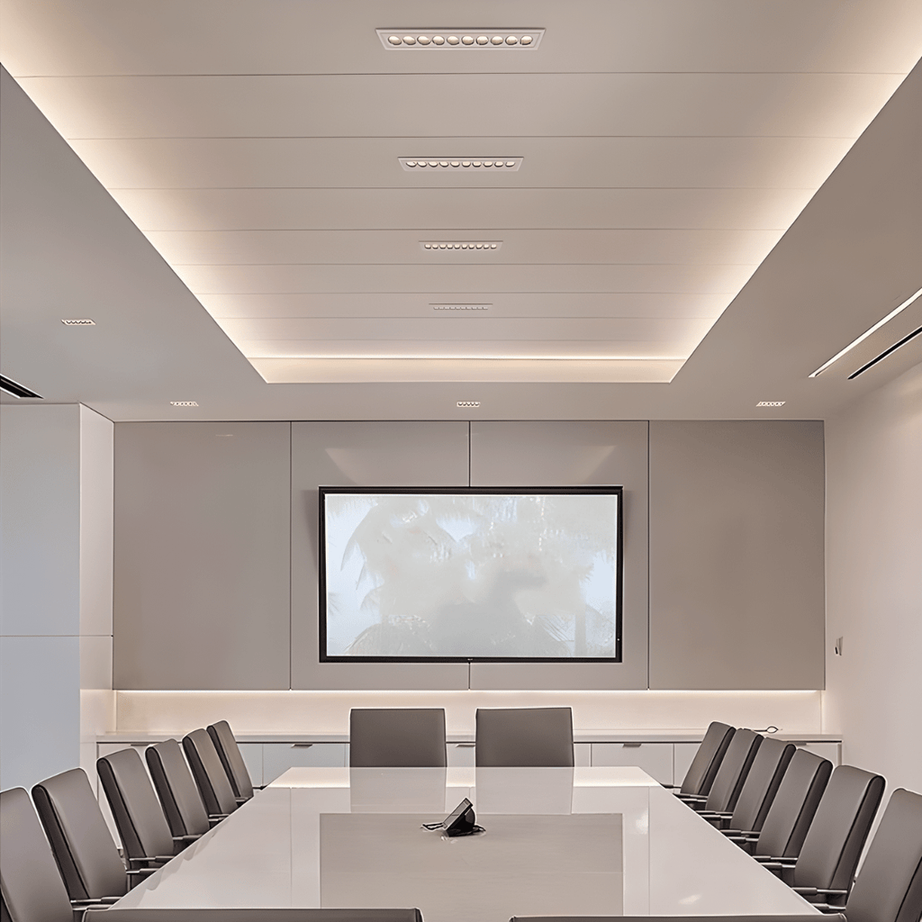 Clérachic slim white recessed downlights stepping down a coffered meeting-room ceiling, with a warm cove glow above a wall-mounted screen.