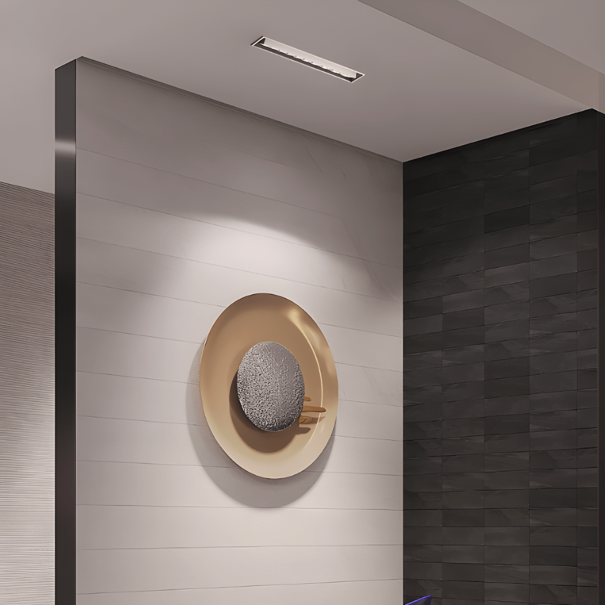 Clérachic slim white recessed downlight in a ceiling above a wall with a round brass-and-stone art piece beside a dark tiled corner.