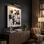 Black Clérachic wall light with a lit tube above a large abstract black-and-white print, next to a dark wood sideboard.