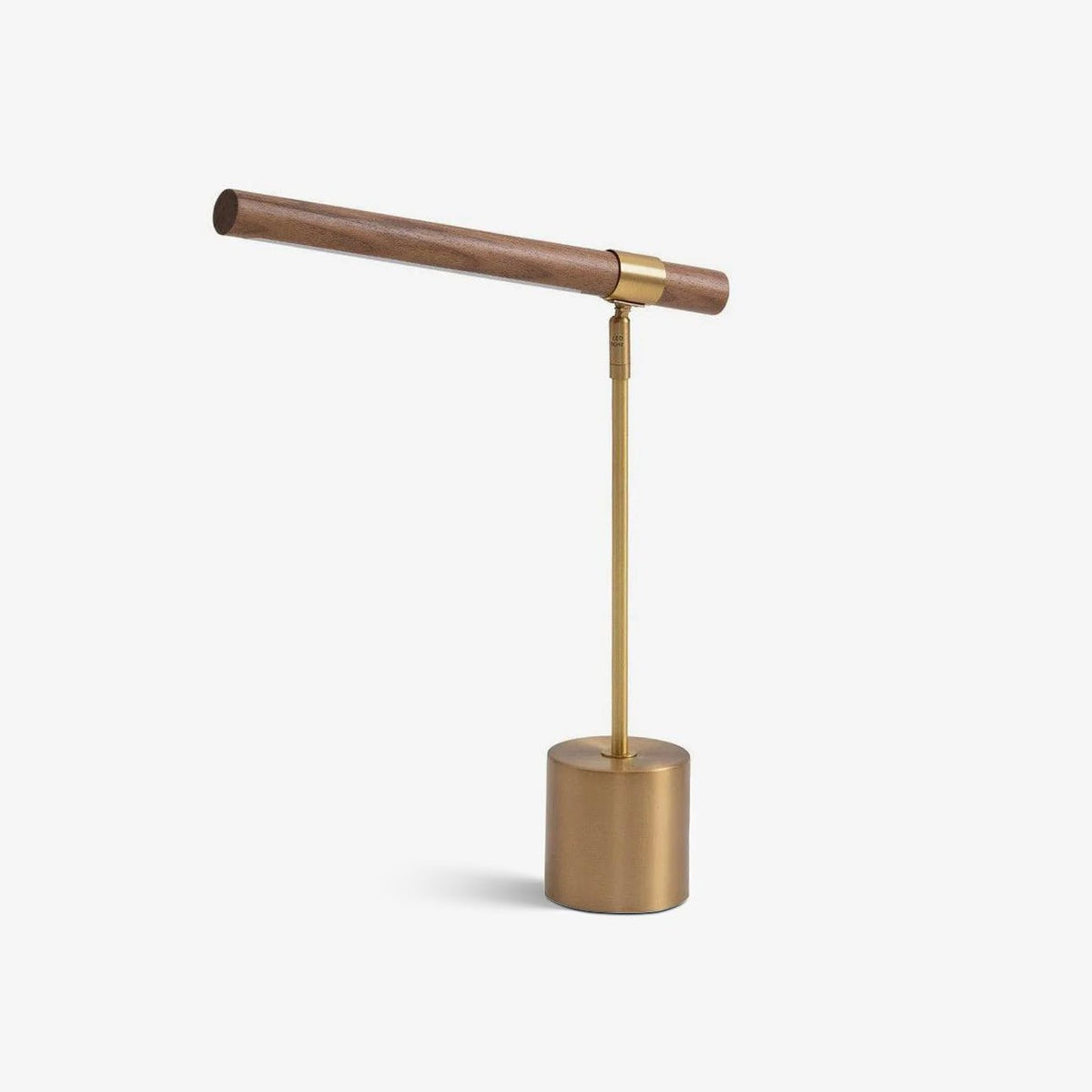 Walnut wood bar on a slim brass stem and round brass base, this Clérachic table lamp on a plain white backdrop.