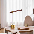 Clérachic table lamp on a round wooden side table beside a book and a small cup, with sheer white curtains behind.