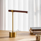 Close framing of this Clérachic lamp on an oak desk, its brass base and stem rising to a walnut bar against white curtains.