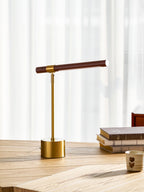 Clérachic lamp with the walnut bar held level, beside a book stack and a small cup on a light wood desk.