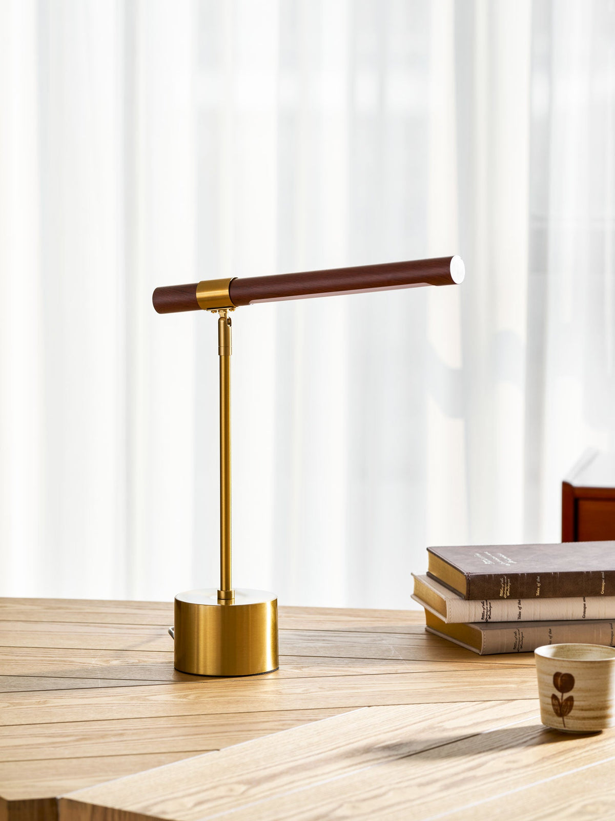 Clérachic lamp with the walnut bar held level, beside a book stack and a small cup on a light wood desk.