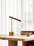 Smaller view of this Clérachic table lamp on a pale desk, its bar tipped down at one end, with books and a cup nearby.