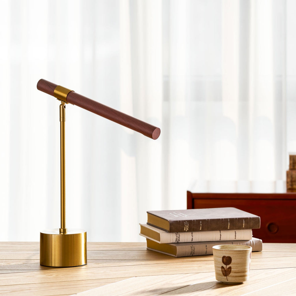 Clérachic lamp with the walnut bar raised at an angle, on a herringbone wood desk beside three stacked books.