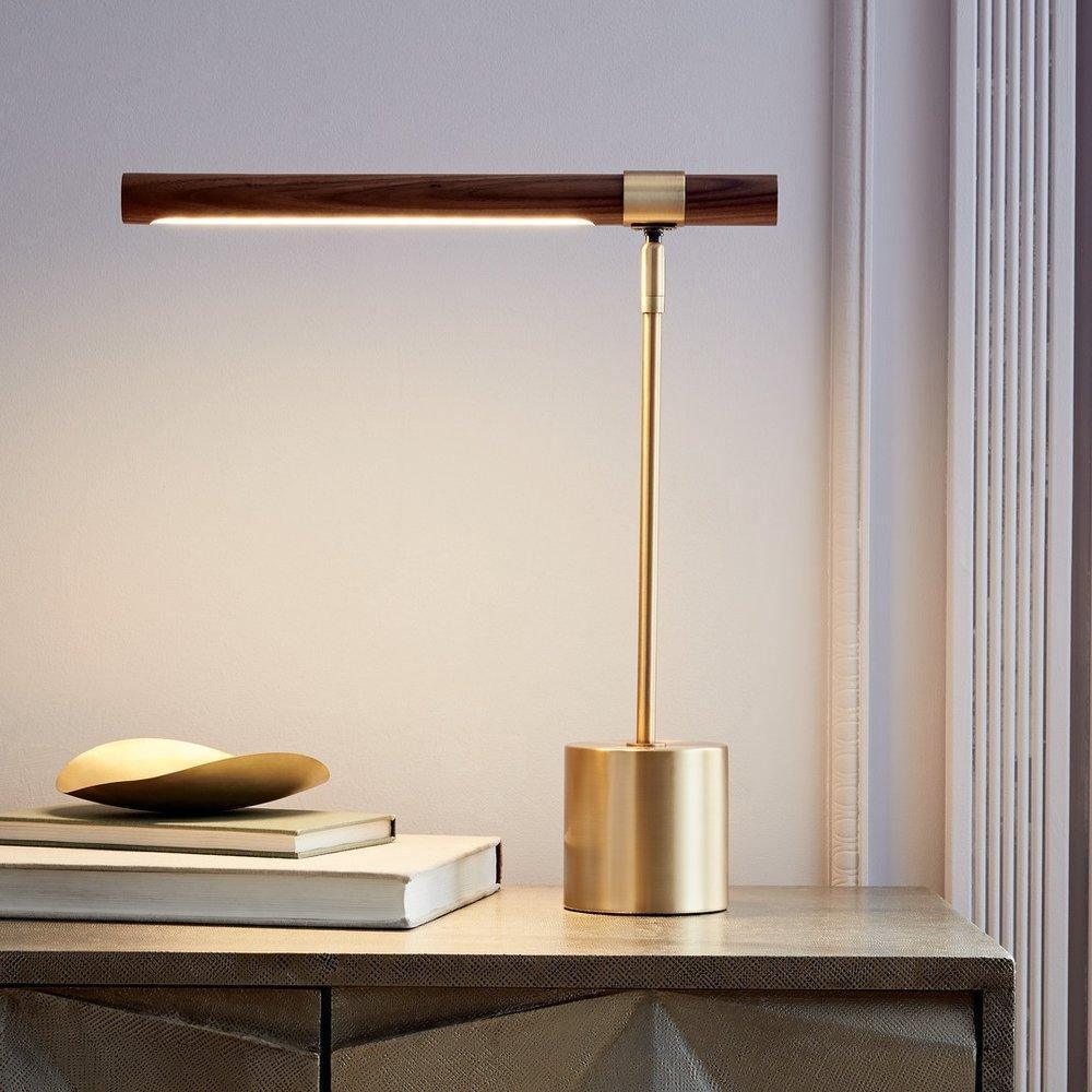 Lit Clérachic table lamp on a textured grey cabinet, the walnut bar glowing underneath, with books and a brass dish beside it.