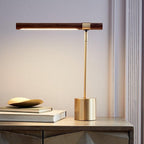 Lit Clérachic table lamp on a textured grey cabinet, the walnut bar glowing underneath, with books and a brass dish beside it.