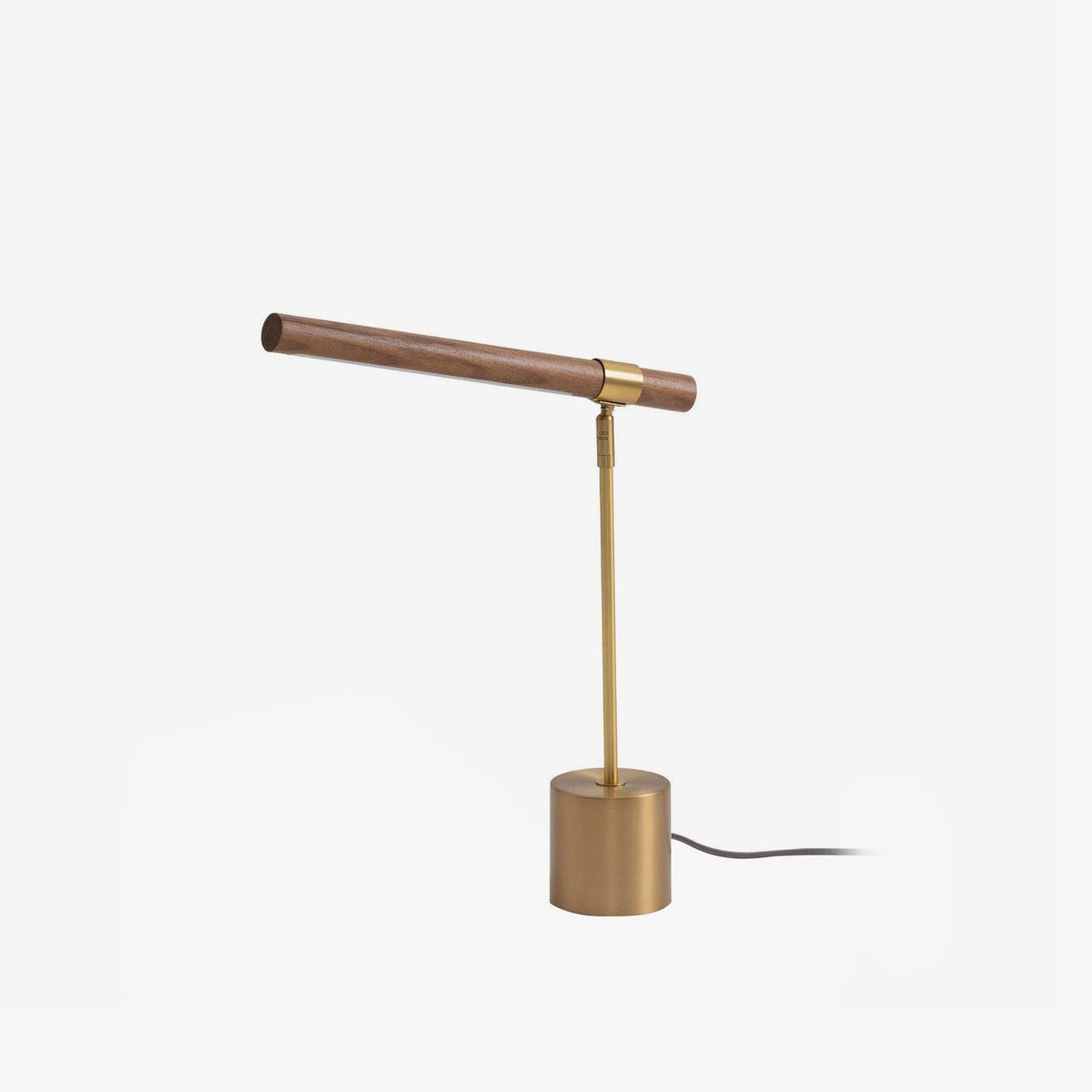 Clérachic table lamp on white, its walnut bar set at a slight angle over a brass stem, with the cord trailing from the base.