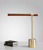 Clérachic lamp on a pale grey backdrop, its walnut bar level above a brass base, with two black books beside it.