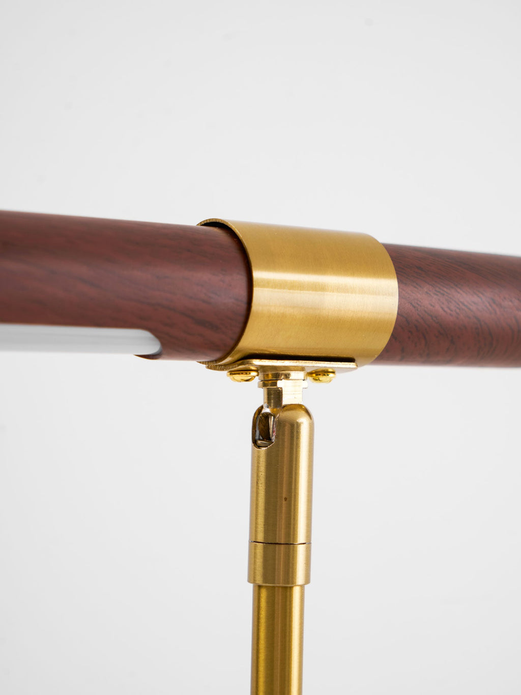 Close view of the swivel joint and brass collar on this Clérachic lamp, with the reddish walnut grain behind.