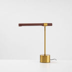 Front view of this Clérachic lamp on a white surface, its walnut bar almost level and the cord trailing off to the right.