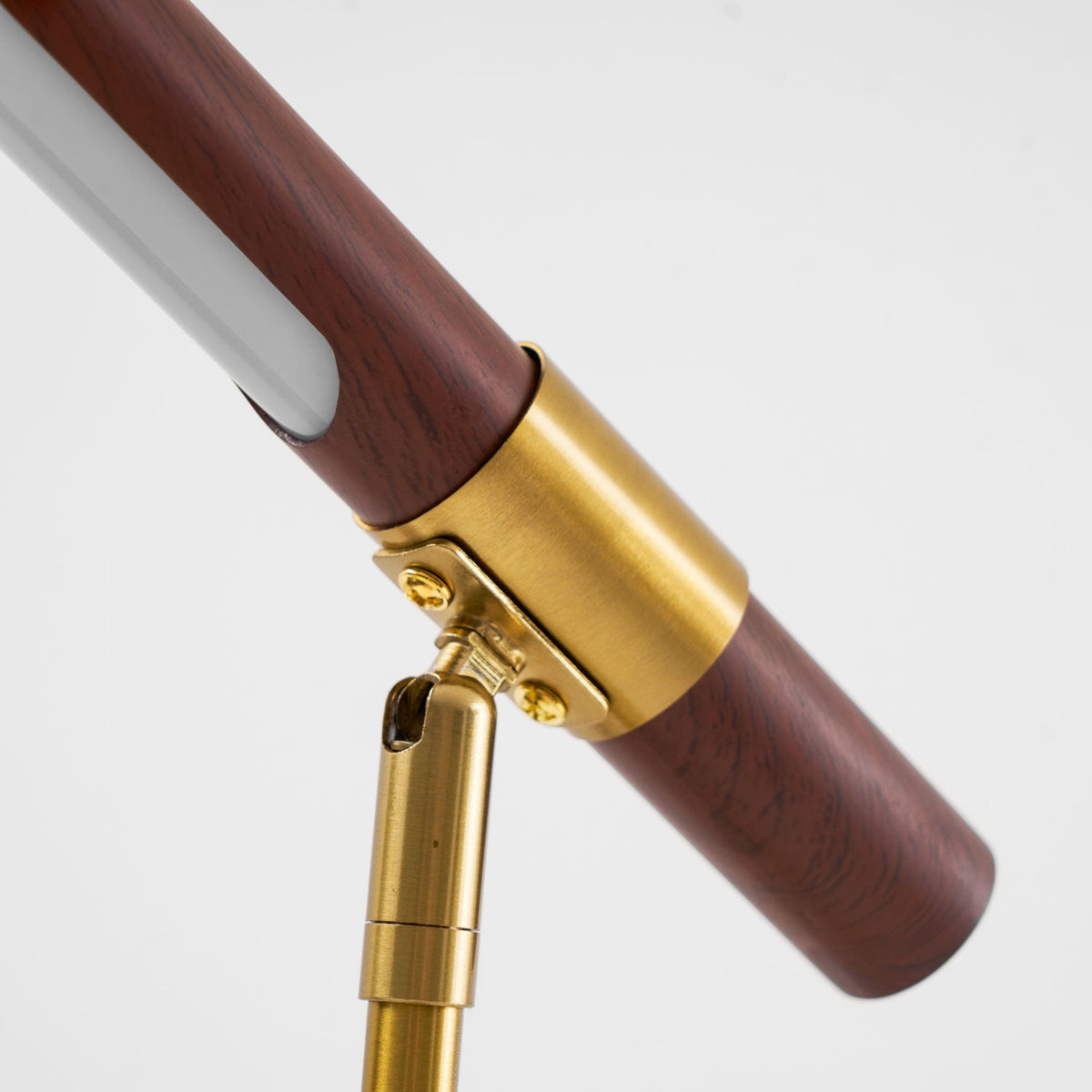 Angled close view of the brass collar, screws and swivel joint on this Clérachic lamp, with the white light strip above.