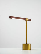 Clérachic lamp with the walnut bar tilted slightly down at one end, lit strip visible, on a white surface.
