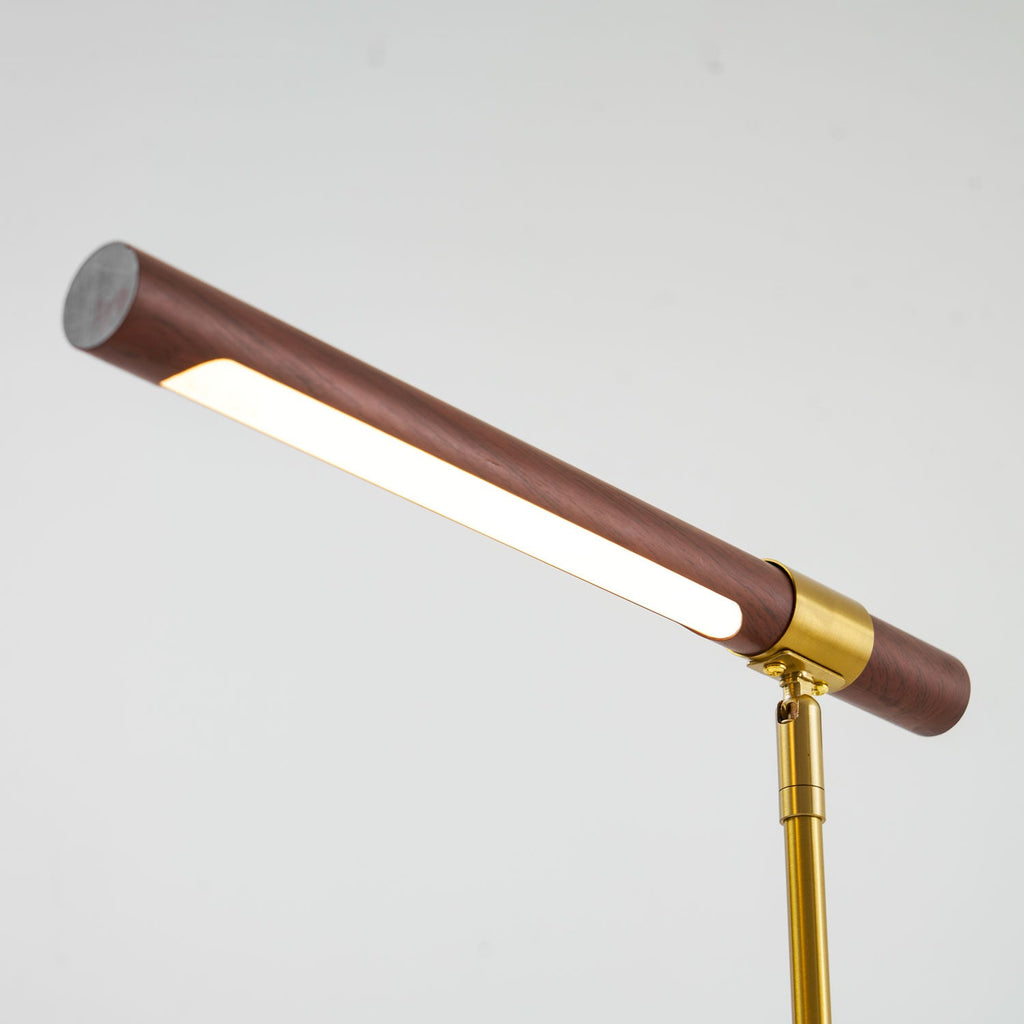 Close view of the lit strip under the walnut bar of this Clérachic lamp, with the brass collar and stem at the right.