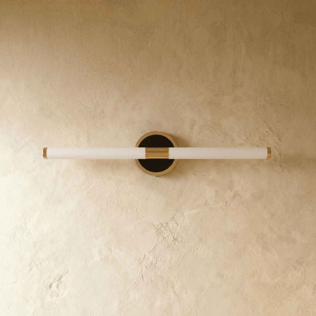 Clérachic slim LED tube wall light switched off, opal white tube and round black and brass wall plate on plaster.