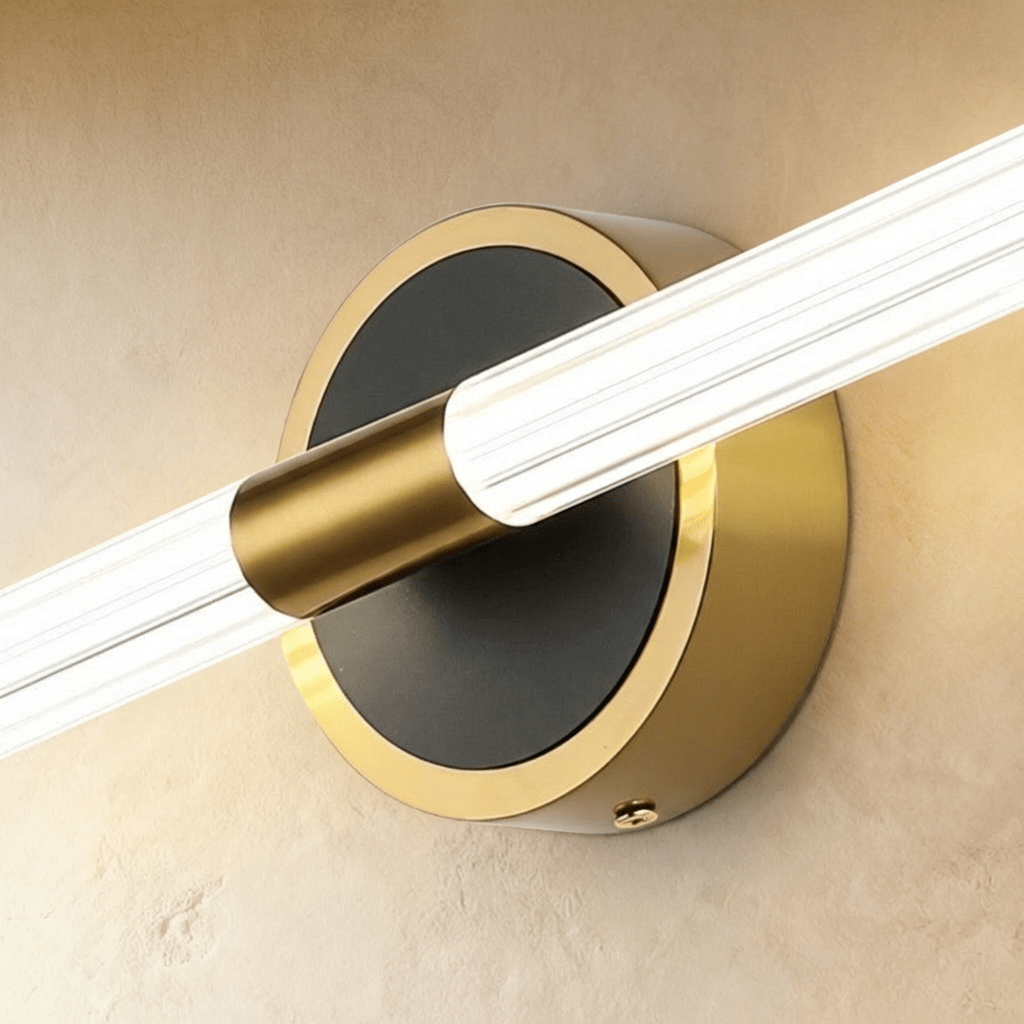Close-up of the Clérachic wall light, a fluted clear tube held by a brass sleeve on a black and brass round plate.