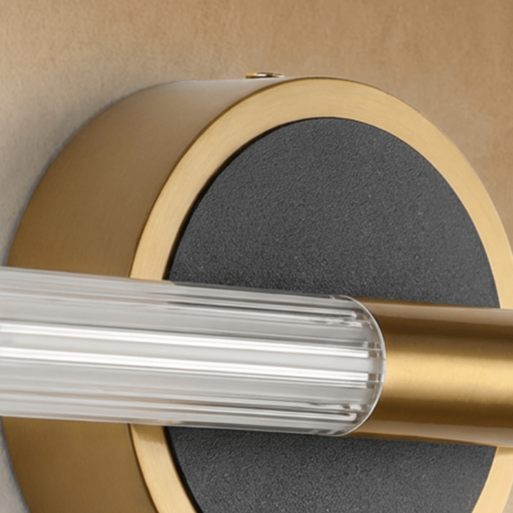 Detail of the Clérachic wall light plate, textured black disc in a brushed brass rim with the fluted tube and brass clamp.