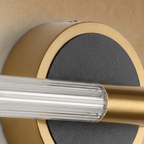 Detail of the Clérachic wall light plate, textured black disc in a brushed brass rim with the fluted tube and brass clamp.