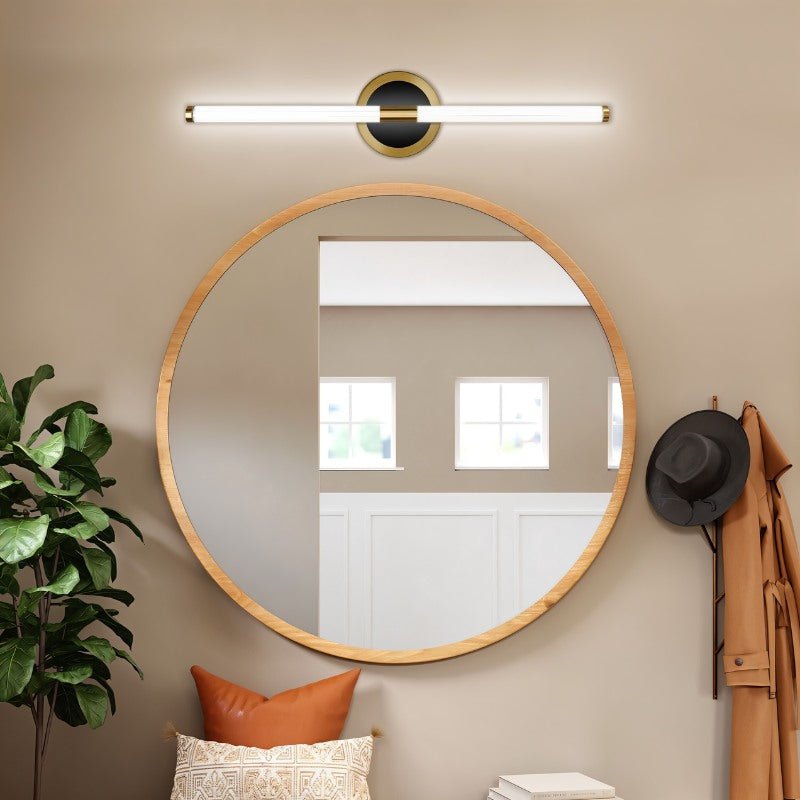 Clérachic LED tube wall light mounted horizontally above a round wooden-framed mirror in an entryway with a coat and hat.