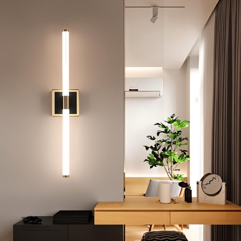 Clérachic LED tube wall light mounted vertically on a square plate beside a pale wooden desk in a bright, airy room.