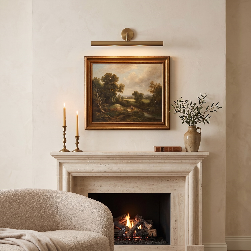 Above a stone fireplace, this Clérachic bronze bar light casts a soft glow over a framed landscape painting, flanked by candlesticks.