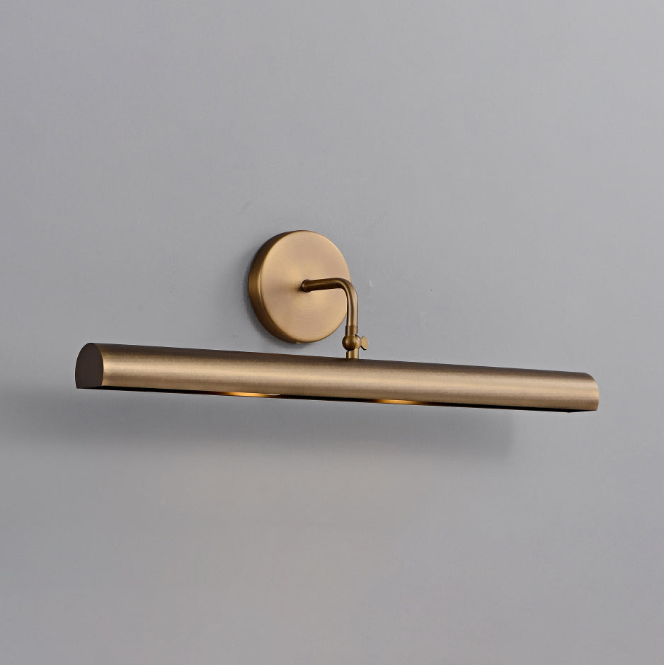 Close view of this Clérachic wall sconce on a grey wall, showing the aged bronze tube, round backplate and curved arm.