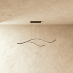 Clérachic black two-arc wavy LED pendant on twin cables, its slim silicone-lit curves glowing softly against a limewash wall.