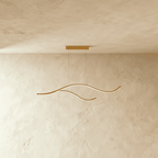 Clérachic gold two-arc wavy LED pendant, lit along its slim curves, hung from a small gold canopy on twin cables.