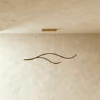 Clérachic gold two-arc wavy LED pendant shown unlit, its brushed aluminium curves hanging below a slim gold canopy.
