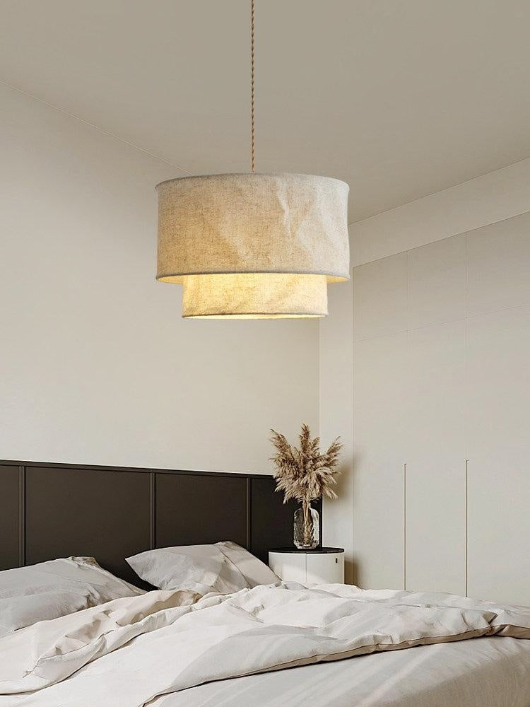 Above a dark upholstered headboard and pampas grass, this Clérachic pendant lights a neutral bedroom.