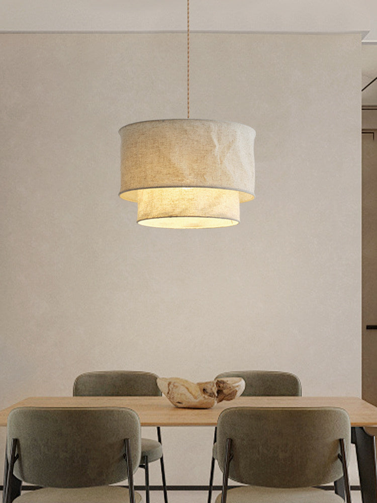Over a wood dining table with green upholstered chairs, this Clérachic pendant glows against a plain wall.