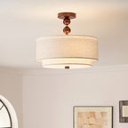 Clérachic walnut-ball stem and layered linen shade glowing softly above a framed picture and part of an arched window.