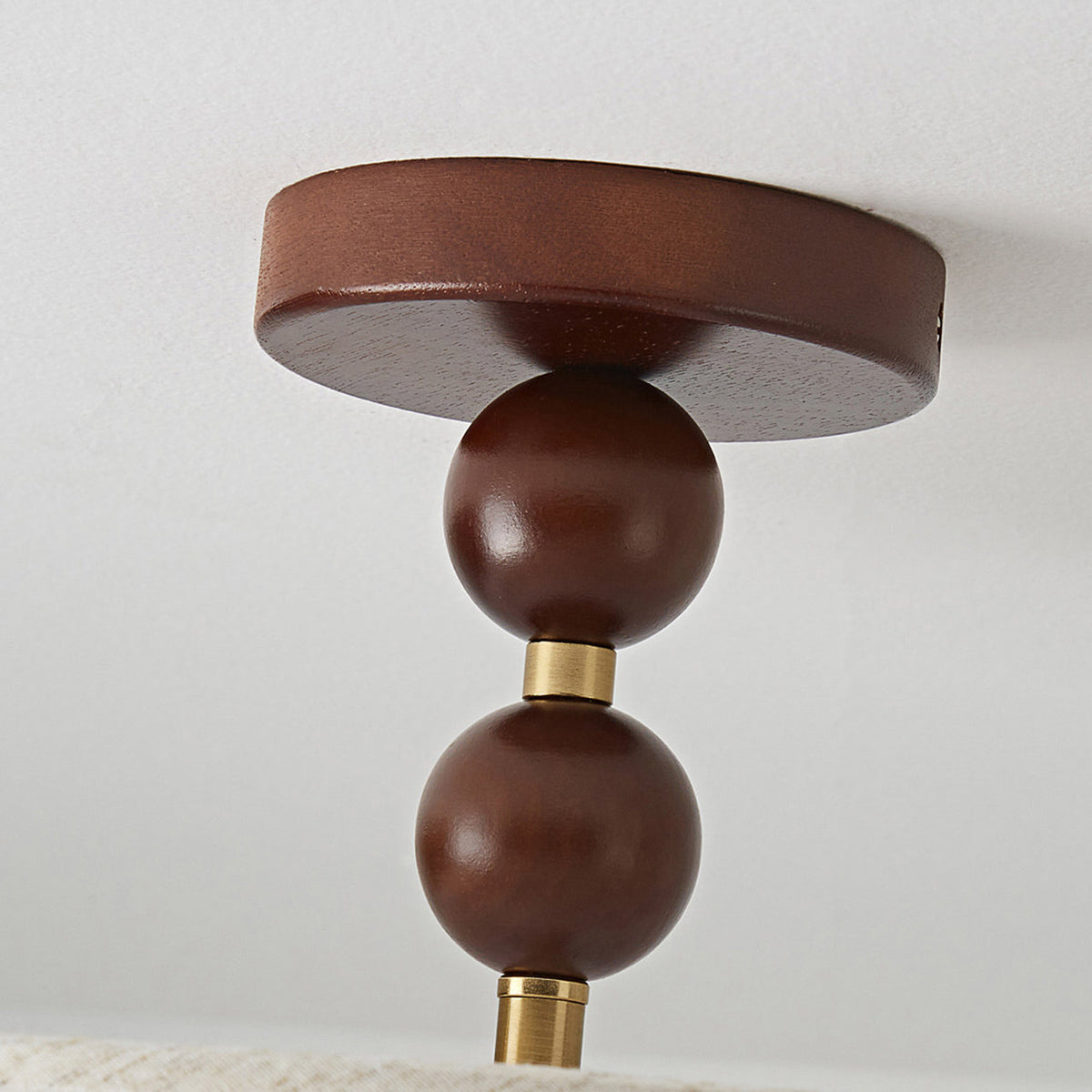 Underside close-up of the walnut canopy, two polished wooden balls and a brass collar on this Clérachic ceiling light.