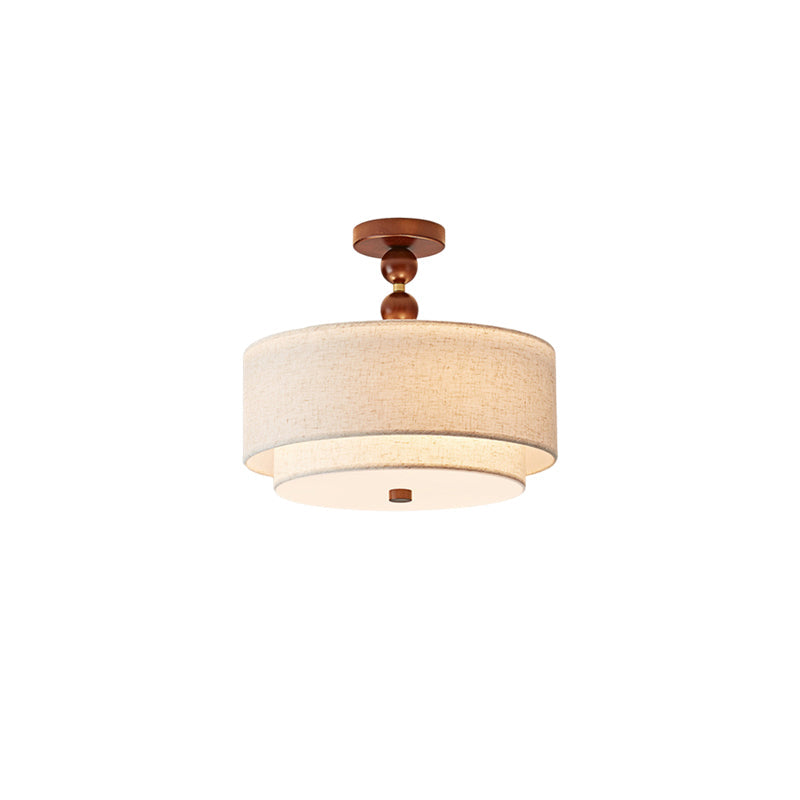 Clérachic walnut and linen light with a two-ball wooden stem, lit softly under its stacked linen shades on a white backdrop.